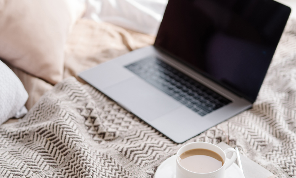 Laptop and cup of tea placed on a bed
